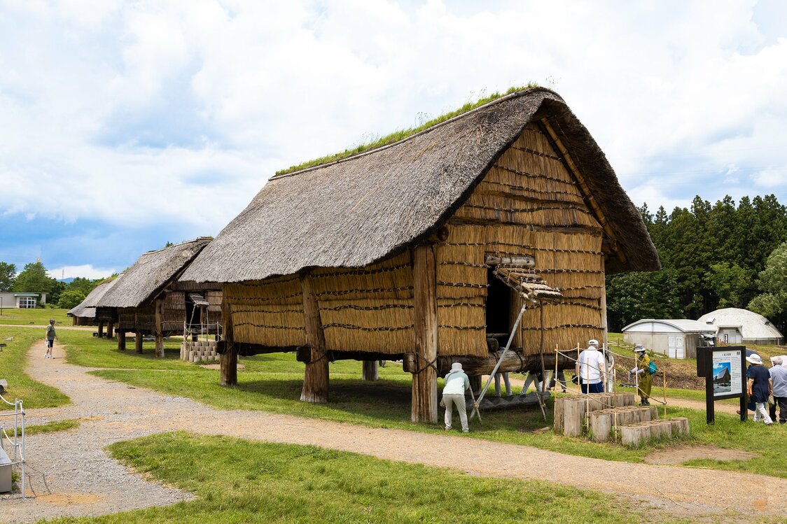 A group of reconstructed raised, pillar-supported buildings at Sannai Maruyama.