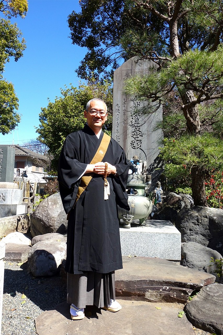 站在供養塔前的服部功志住持（筆者攝影）