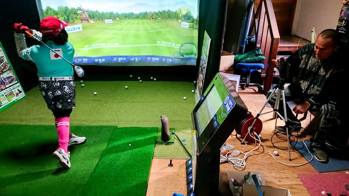 Sutō Miroku trains with her father Ken’ichi in the family garage using a simulator that can measure distance, spin, and ball speed.