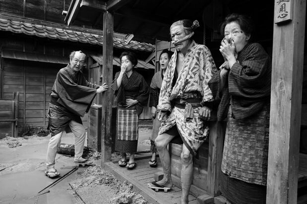 肥汲みが来る前に大雨で厠があふれ、臭いに閉口する長屋の住人たち。阪本作品の常連、石橋蓮司（左端）が元「早桶屋」（手早く棺桶を作る職人）の孫七役で出演　©2023 FANTASIA