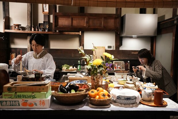 食事の支度をする義母をよそに、台所でも「取材」に没頭するまどか。京町家の空間を存分に生かした画面作りも作品の魅力に ©2025「ぶぶ漬けどうどす」製作委員会