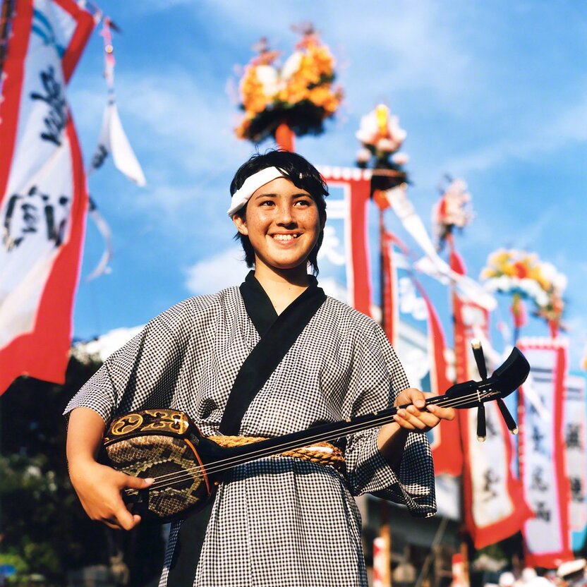 在石垣岛的“丰年祭”上，手持三线琴的高中生