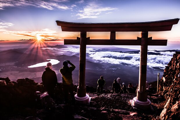 Escaladores disfrutan del amanecer desde la cima del monte Fuji. (© Pixta)