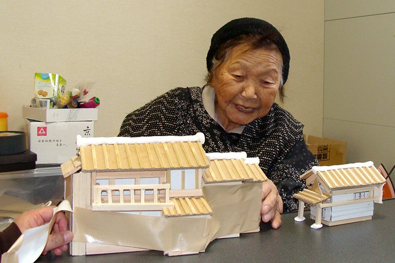 佐佐木YASU子正在桑折町的临时住宅内制作浪江町中自家房子的模型（2013年，笔者摄影）