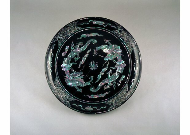 Bandeja de laca negra con incrustaciones de nácar formando nubes y dragones. Datada entre los siglos XVIII y XIX. En el centro de la bandeja, los dragones portando la mítica piedra chintamani y la nube irisada de los buenos auspicios, elementos ambos de la tradición budista. (Colección del Museo de Arte de Urasoe)