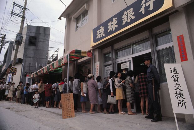 Des citoyens font la queue dans une banque pour échanger des dollars contre des yens avant le retour au Japon. Naha (Jiji Press)