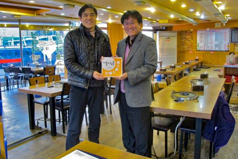 A restaurateur (left) stands with a welfare center social worker after signing up for the “Beautiful Neighbors” program.