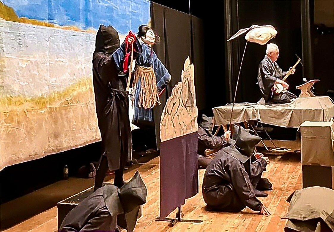 Her face hidden from the audience, Chloé is dressed all in black. She holds a puppet representing the pirate Koxinga in Chikamatsu Monzaemon’s play about the historical figure on October 19, 2024, in Hirado, Nagasaki. The narrator is on the right, holding a shamisen. (Courtesy of Chloé Viatte)
