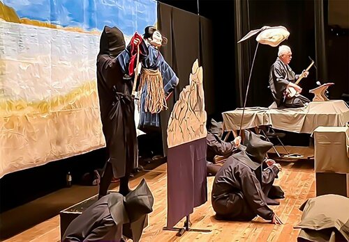 Son visage caché des spectateurs, Chloé excelle incognito dans sa panoplie noire de marionnettiste (au centre). Elle tient la marionnette représentant le pirate Kokusen’ya (Coxinga), personnage historique et héros de la pièce Kokusen’ya Kassen, de Chikamatsu Monzaemon, le 19 octobre 2024 à Hirado, dans la préfecture de Nagasaki. Le recitant est à droite, avec son shamisen.
