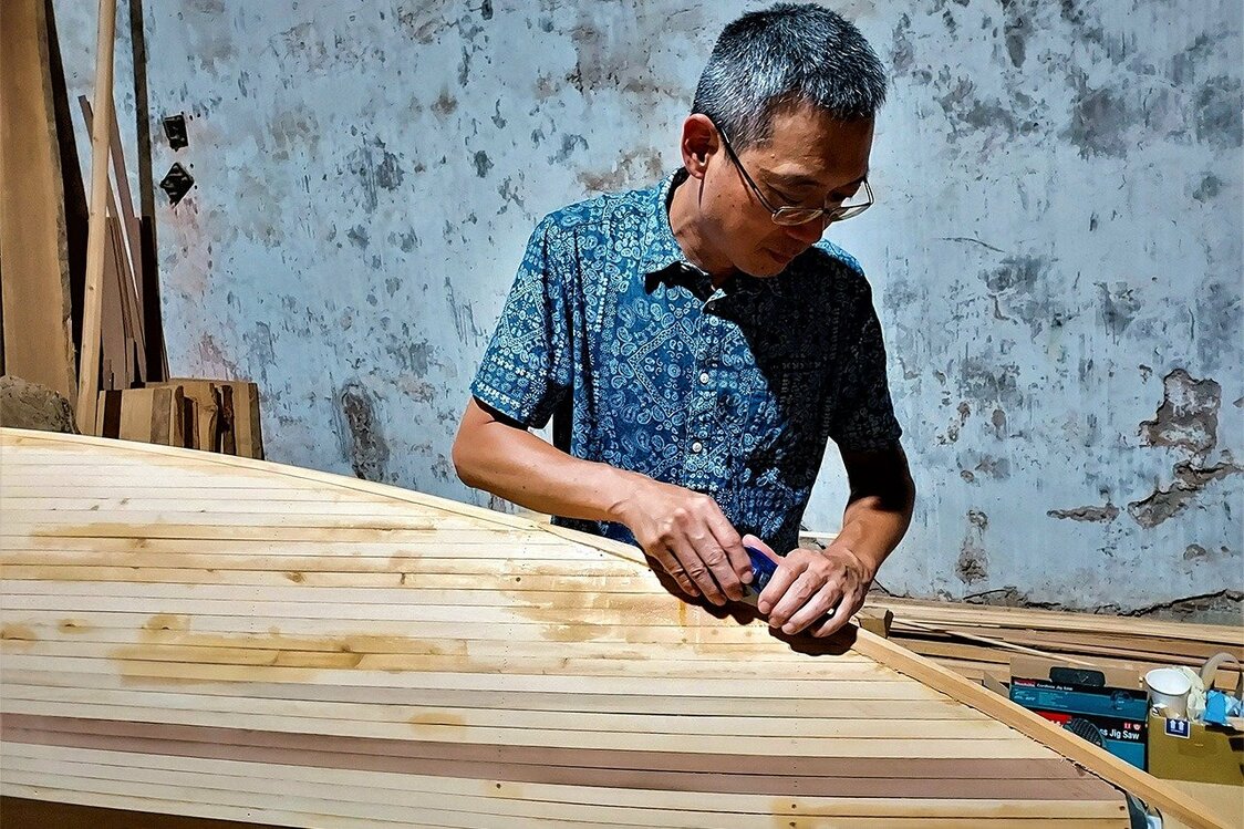 陳冠宇仔細研磨用細長木板連接而成獨木舟