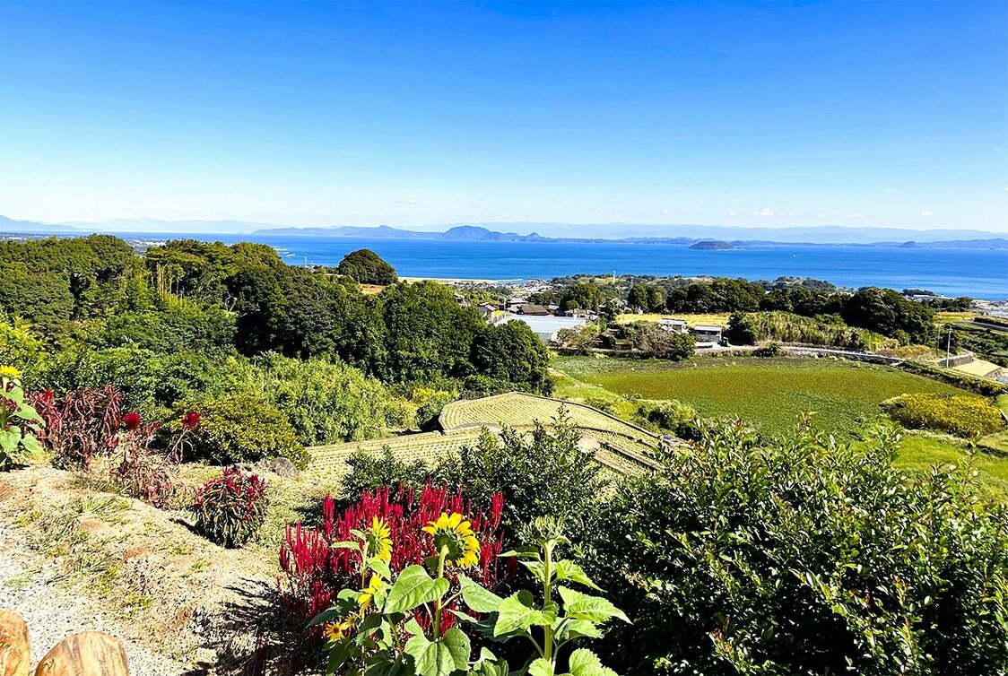 La statue se dresse sur une colline le long de la route touristique Unzen Green Road. La mer d’Ariake s’étend en contre-bas avec une vue idéale sur les ruines du château de Hara.