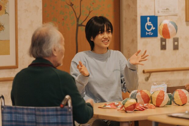 An trabaja con ánimo en una residencia de ancianos donde la presenta Kirino. © 2023 Comité de producción de An no koto