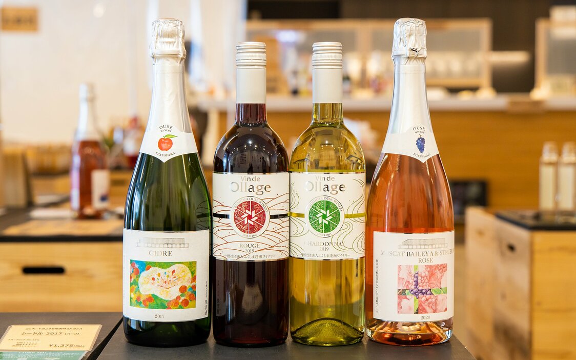 Бутылки Vin de Ollage справа окружены Muscat Bailey A & Steuben Rosé 2020, игристым вином, изготовленным из винограда, выращенного в городе Фукусима Айдзу-Вакамацу, и сидром 2017 слева