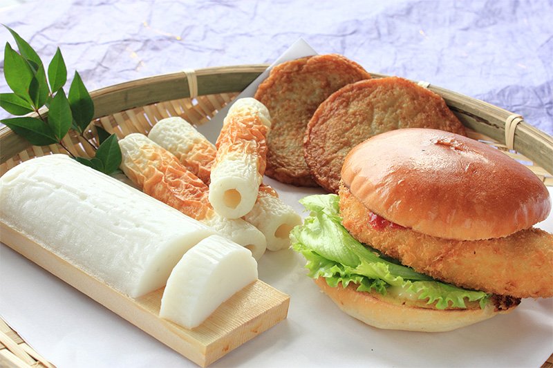 A la izquierda, yakinuki kamaboko; al fondo, chikuwa, con forma de cilindro, y hiraten; a la derecha, hamburguesa de kamaboko frito.