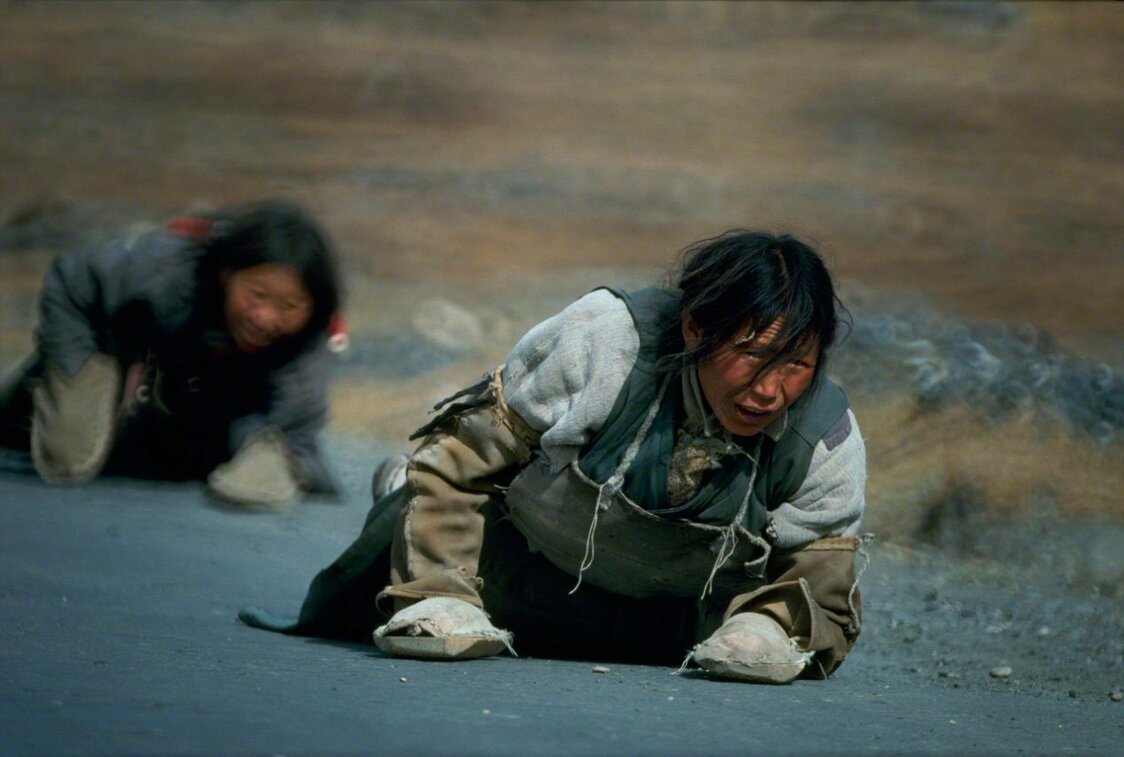 Pèlerins progressant à plat ventre en chantant un sutra sur le chemin de Lhassa, Tibet, en 1989. (Extrait de « Le rêve de la Longue Marche : la Chine, terre du réalisme »)