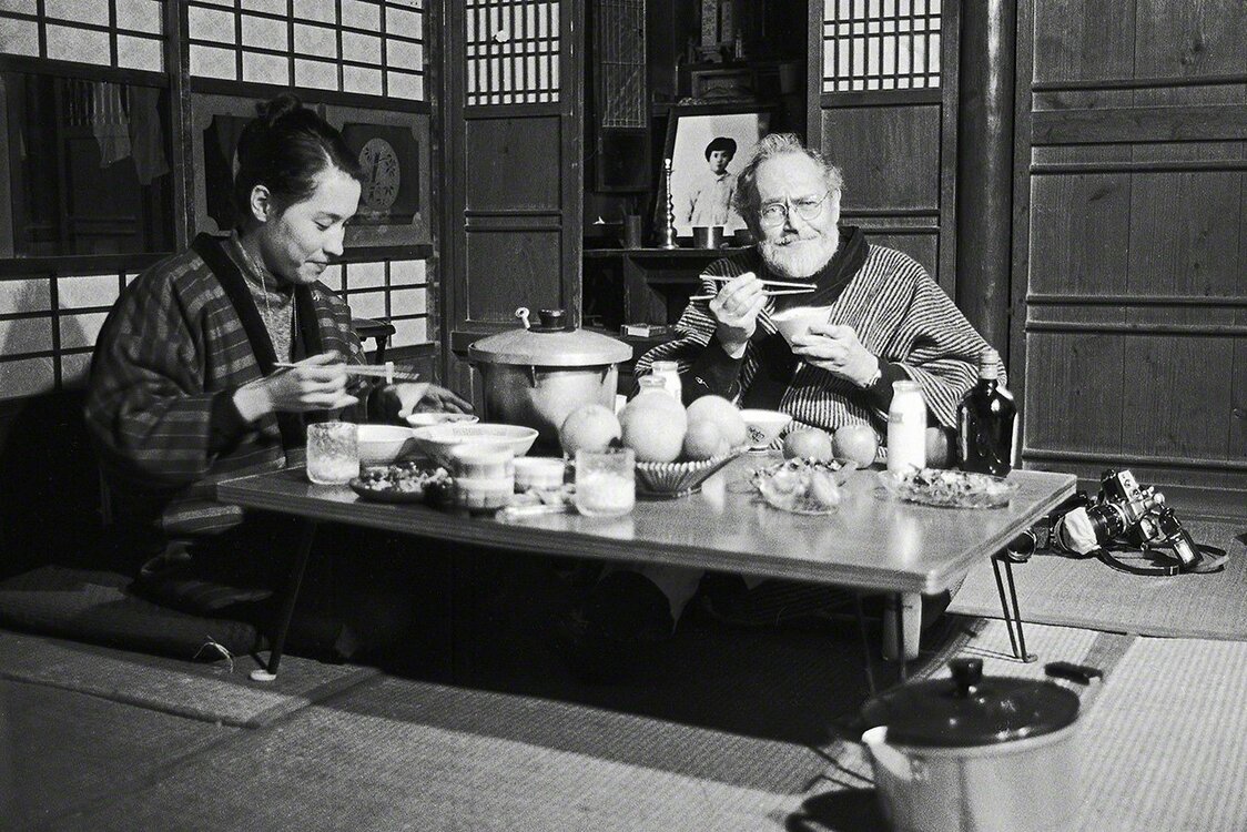 William Eugene Smith et son épouse Aileen Mioko Smith en train de dîner dans la salle de séjour de leur maison de Minamata. Ils portent l’un et l’autre la veste japonaise ouatée (dotera) utilisée traditionnellement par les Japonais en hiver. (Photo prise en 1972)