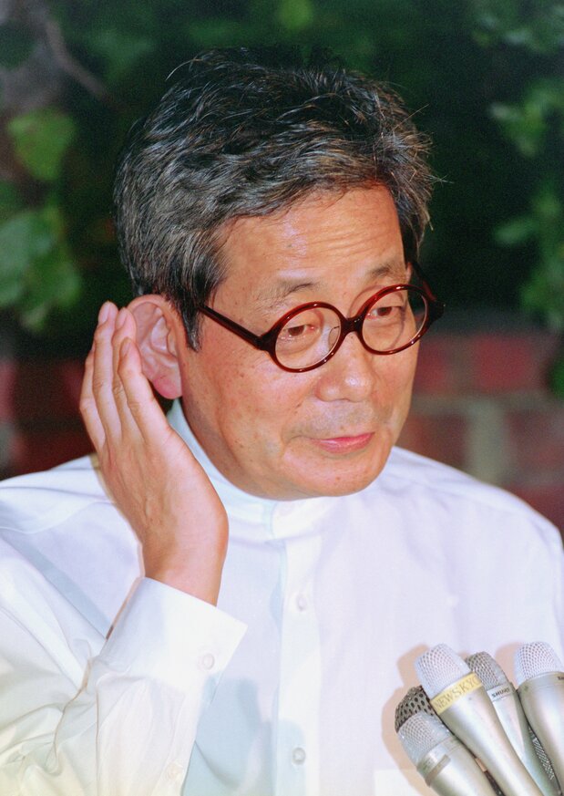 Ōe Kenzaburō speaks to reporters outside his house after winning the Nobel Prize in Literature on October 13, 1994. (© Jiji)