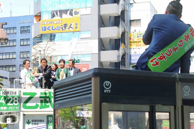 Nemoto Ryōsuke, del Partido Tsubasa no Tō (a la derecha, delante), interrumpe un acto de campaña para las elecciones parciales en el distrito 15.º de Tokio en el que participan Ototake Hirotada (a la izquierda), el líder del Partido Democrático para el Pueblo Tamaki Yūichirō (segundo desde la izquierda) y la gobernadora de Tokio Koike Yuriko (cuarta por la izquierda) frente a la estación de Kameido, en la capital, el 16 de abril de 2024. (© Jiji)