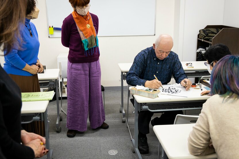 即興で円形にデザインしたアラビア文字をつづる。本田さんがお手本を書き始めると、自然と生徒が集まってきて、完成と同時に拍手が起こる