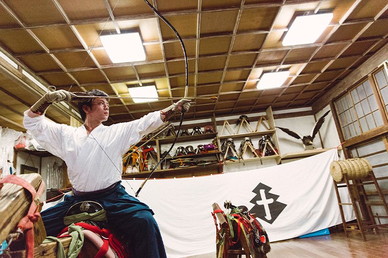 Ogasawara Kiyomoto stands astride a mokuba wooden horse during a yabusame class.