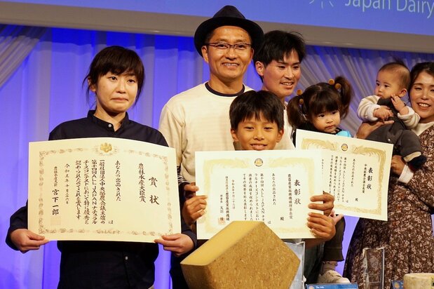 次男のルカ君と「第14回ALL JAPANナチュラルチーズコンテスト」の表彰式に立つ松原さん(中央)。銀メダルに当たる農畜産業振興機構理事長賞を獲得した 写真:浮田泰幸