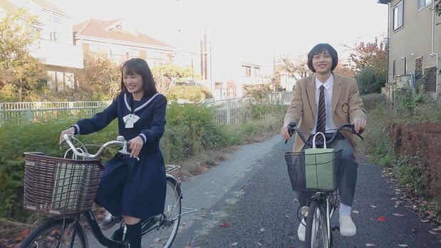 神田川沿いを自転車で行く舞と智樹。再会の喜びが抑えられず、葬式帰りとは思えぬほどほがらかだ ©2021 Sunny Rain