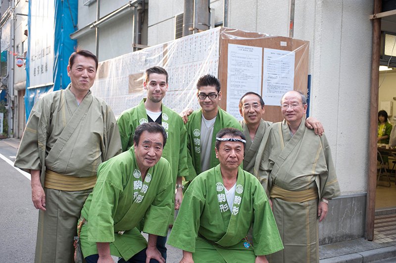 駒形町会の前をたまたま通りかかったオーストリア人の、BryanさんとFrancyさん【中央】。「日本に着いて間もないし、時差ボケが残っているけど、祭りの輪に入れて最高！」思わず半纏を借りてポーズ。浅草の人びとはこうやって外の人も温かく受け入れてくれる。