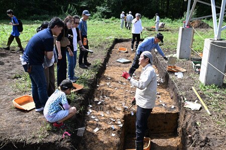 People listen to researcher Sadakatsu Kunitake (front right) at the Kanmuri ruins in the city of Hatsukaichi, Hiroshima Prefecture, western Japan, on Sept. 5.