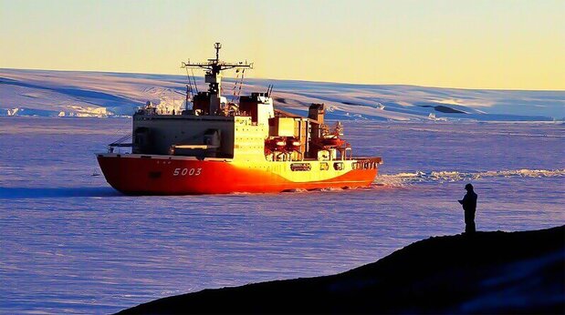 The icebreaker Shirase approaches the Japanese research base on East Ongul Island against the dramatic backdrop of the Antarctic land mass.