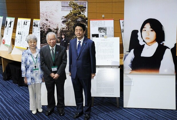 拉致被害者横田めぐみさんの写真パネル展を訪問した安倍晋三首相(右)。中央は横田滋さん、左は早紀江さん=2014年6月10日、東京・永田町の衆院第1議員会館(時事)
