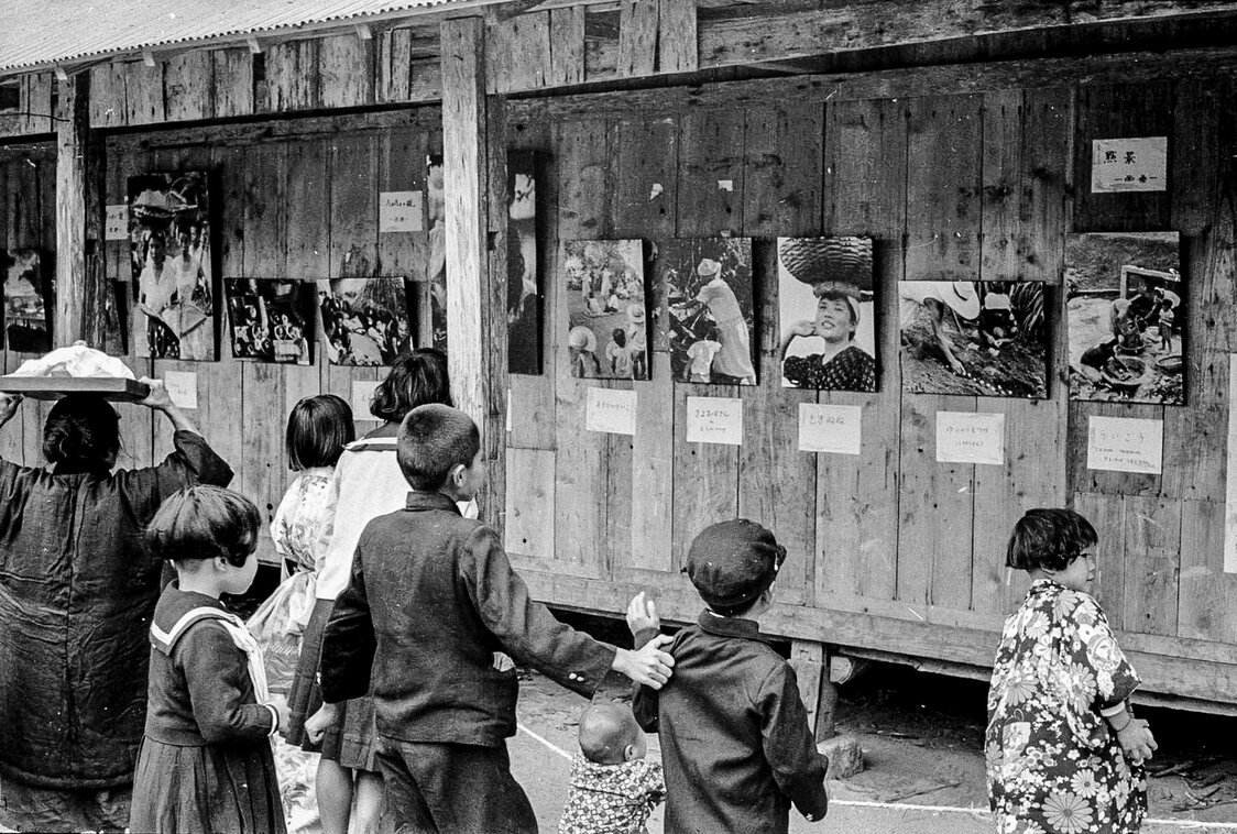 Жители острова рассматривают фотографии Девяти научных обществ, сделанные в 1957 году. Фотоаппараты в то время были редкостью, и сами фотографии были непривычны (© Хага Хидэо)