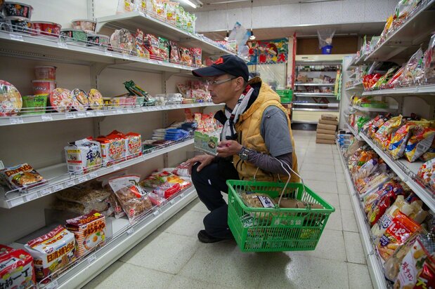 Takada thinks about the preferences of the customers he will be visiting that day in choosing the products to load in the grocery truck. (© Ōnishi Naruaki)