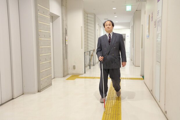 Professor Fukushima walks down the corridor of the University of Tokyo Research Center for Advanced Science and Technology. He is able to use the toilet unassisted. (© Hanai Tomoko)