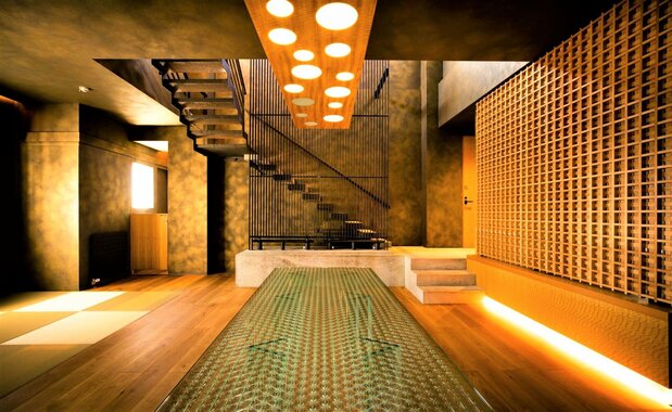 The first floor has modern Japanese dining and living rooms. The bathroom, with glass walls on three sides, looks out over the Hirado Ōhashi bridge. (© Noroshi)