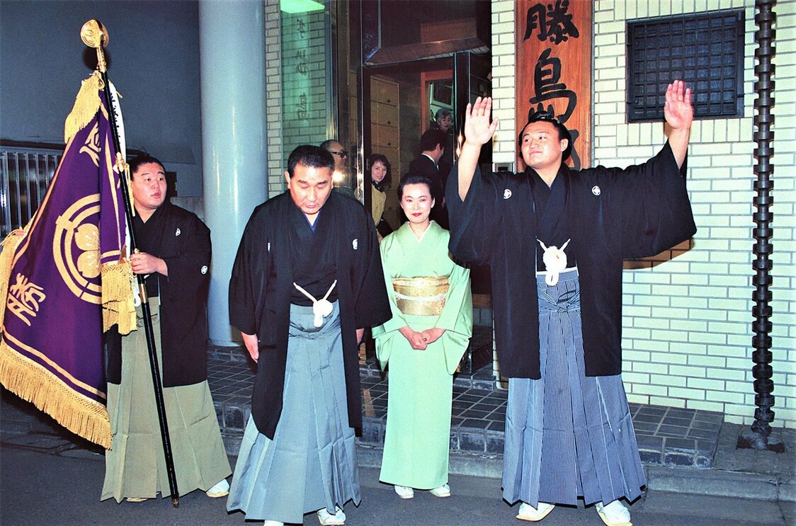 At right, Takahanada (later the yokozuna Takanohana) celebrates becoming the youngest-ever rikishi to win a basho, the 1992 New Year tournament. From left, his older brother Wakahanada (who would go on to be the yokozuna Wakanohana) holds the victory banner, with the brothers’ parents, the oyakata Fujishima (later Futagoyama) and Fujita Noriko, between them. Taken in Nakano, Tokyo, on January 26, 1992. (© Jiji)