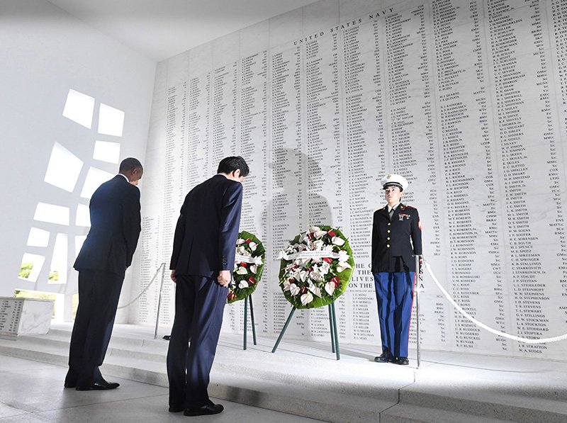 El primer ministro Abe Shinzō y el presidente Barack Obama guardan silencio ante el monumento en el que están inscritos los nombres de las víctimas del ataque a Pearl Harbor en el Memorial del USS Arizona, el 27 de diciembre en Oahu, Hawái. (© Jiji)