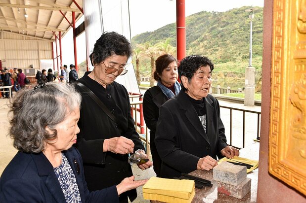 以沖繩獨有的黑色線香與黃色紙錢供養死者的家屬們，2018年3月1日，基隆市（筆者攝影）