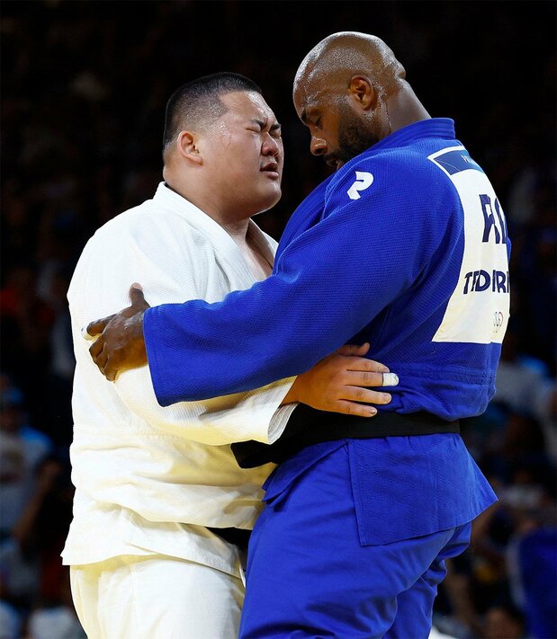 Saitô Tatsuru et Teddy Riner au terme de la longue épreuve de judo par équipe mixte qui a vu le Français triompher par deux fois. (Reuters)