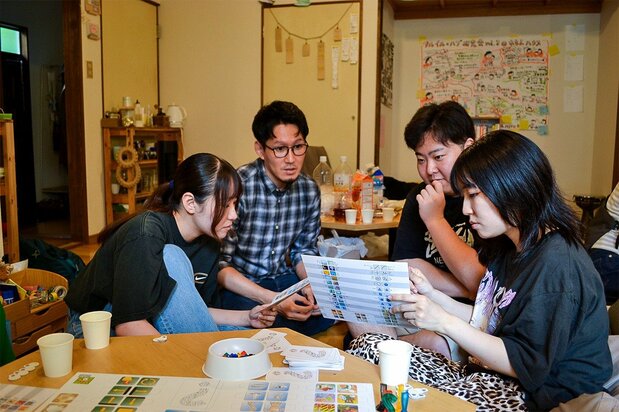 れもんハウスで渡慶次さん(左から2人目)が開いたゲーム大会。参加者は真剣にルールを読みこむ