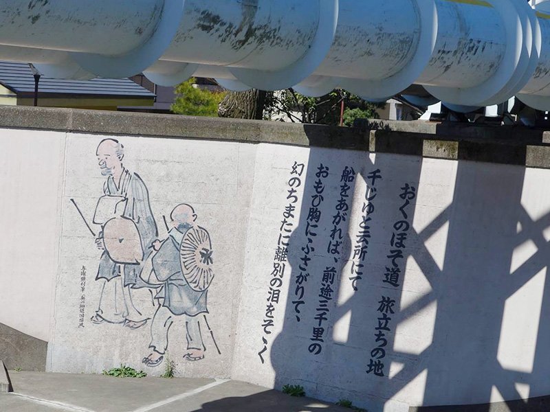 El mural de Bashō y Sora, en parte oculto por las tuberías de agua.