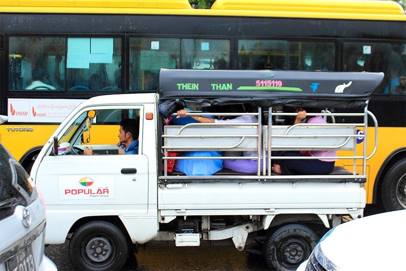 Workers for a small company returning home on the back of a truck with attached roofing.