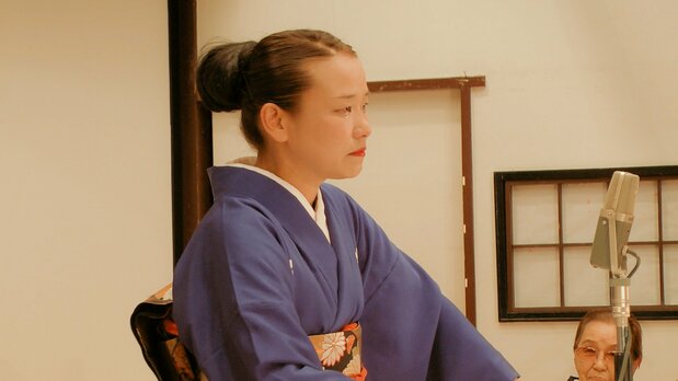 港家小そめ(みなとや・こそめ) 埼玉県出身。東京・台東区のちんどん屋二代目瀧廼家五郎八(たきのや・ごろはち)親方に弟子入り。1997年に独立、「ちんどん月島宣伝社」旗揚げ。ちんどん屋として日本各地で活動。2013年9月、港家小柳に入門し、1年後に初舞台。19年6月木馬亭にて名披露目興行。© Passo Passo + Atiqa Kawakami