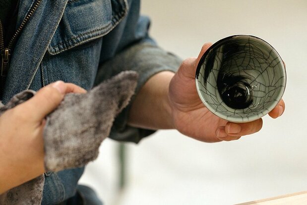Rubbing sumi ink into the naturally crazed surface of a pot to emphasize the effect