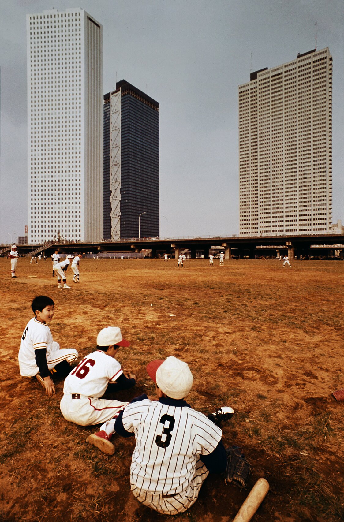 1974年3月の新宿副都心。高層ビルの近くにある公園で少年野球の練習が行われていた。ビルは左から、新宿住友ビル、新宿三井ビル、京王プラザホテル（時事）
