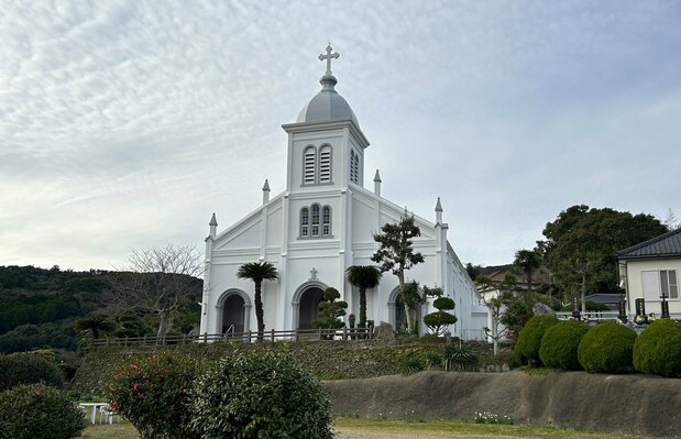La iglesia de Ōe, construida en 1933 por iniciativa del sacerdote francés Frédéric Garnier y de los creyentes de la aldea. Con sus blancas paredes y silueta de inspiración románica, es la “Iglesia de Monte”, en contraste con la vecina de Sakitsu, conocida como la “Iglesia de Mar”. (Fotografía: Amano Hisaki)