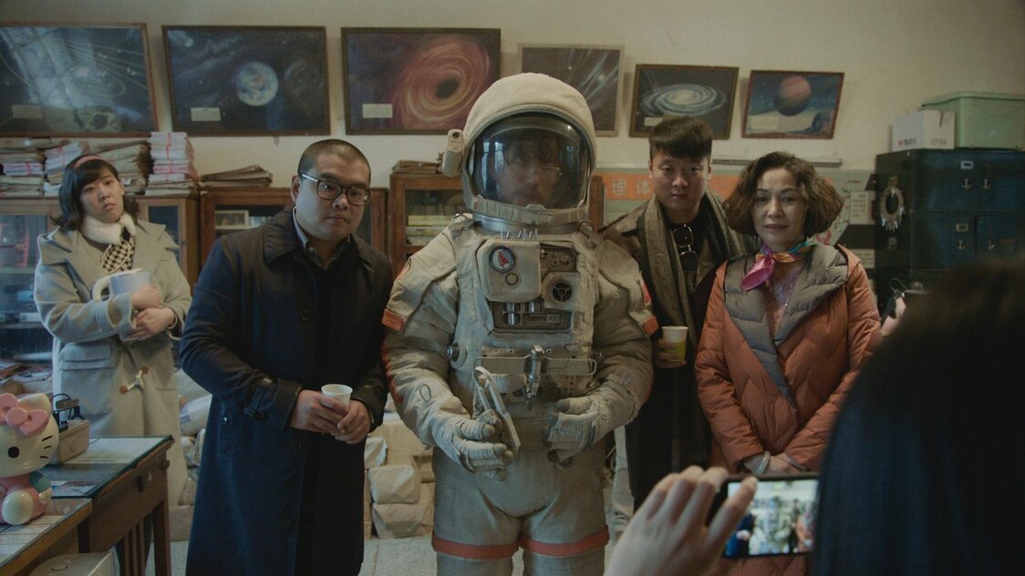 支援者に請われて宇宙服を着るタン編集長。このあと事件が起こる　©G!FILM STUDIO[BEIJING]Co.,LTD. ALL RIGHTS RESERVED.