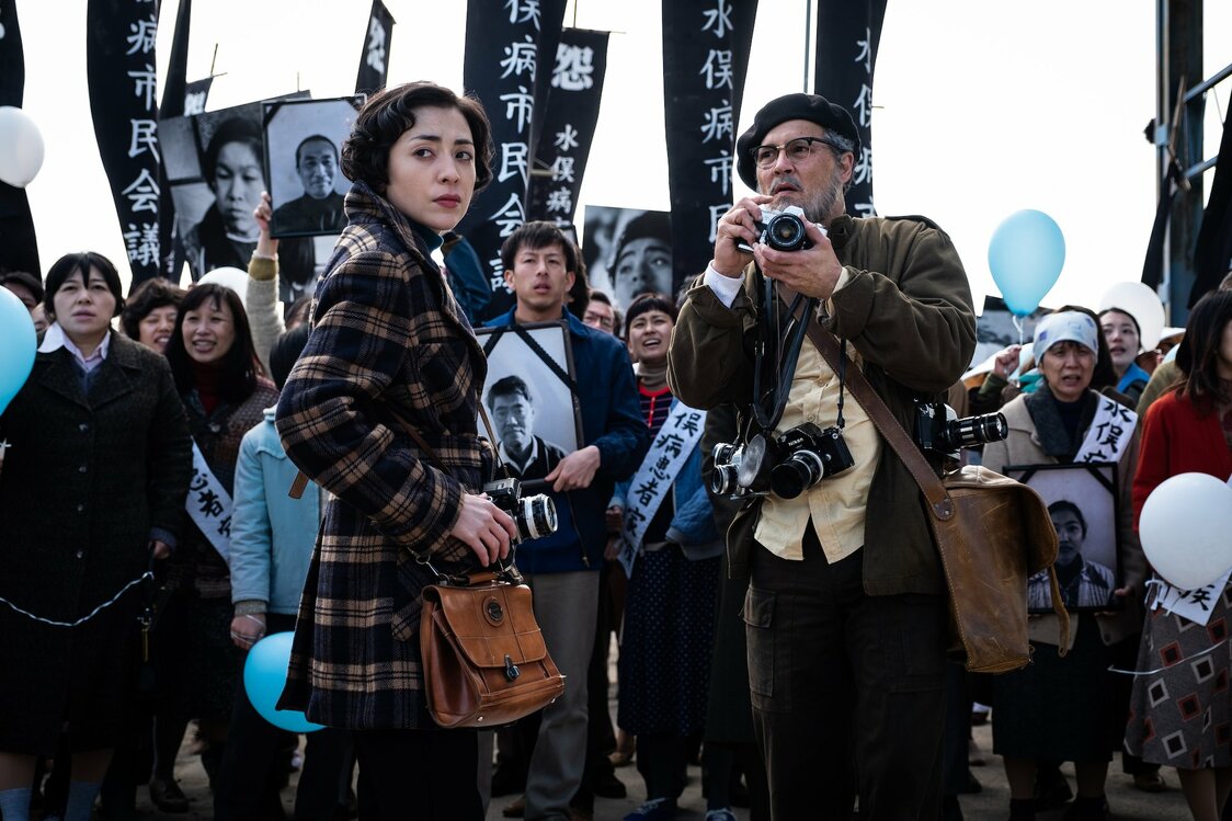 La scène de la manifestation avec des bannières noires et le mot “怨” (rancune) en blanc ©2020 MINAMATA FILM, LLC ©Larry Horricks