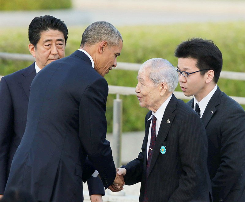 El entonces presidente estadounidense Barack Obama (centro izquierda) estrecha la mano e intercambia unas palabras con Tsuboi Sunao (centro derecha), superviviente de la bomba atómica, en el Parque Memorial de la Paz, 27 de mayo de 2016, Hiroshima. (Jiji Press)