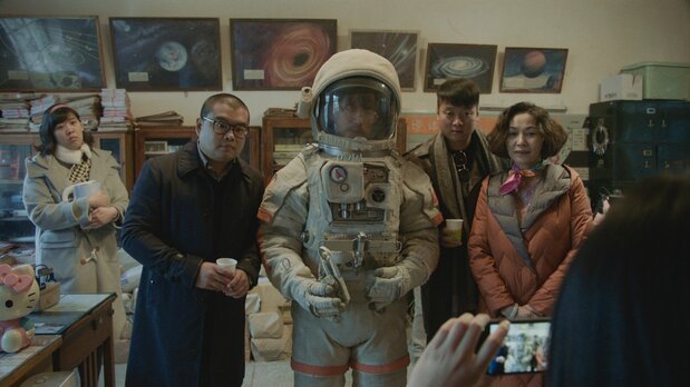 支援者に請われて宇宙服を着るタン編集長。このあと事件が起こる　©G!FILM STUDIO[BEIJING]Co.,LTD. ALL RIGHTS RESERVED.