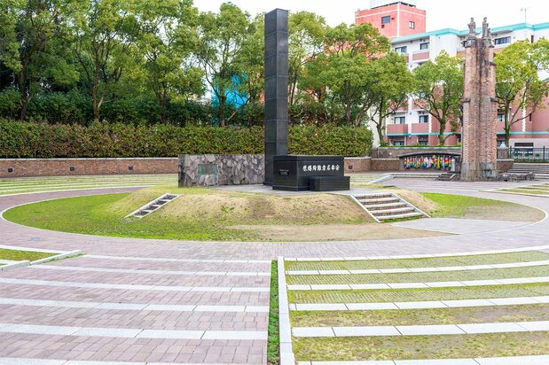 The monolith indicates the hypocenter of the atomic blast. In the background to the right is a section of wall remaining from Urakami Cathedral. (© Pixta)